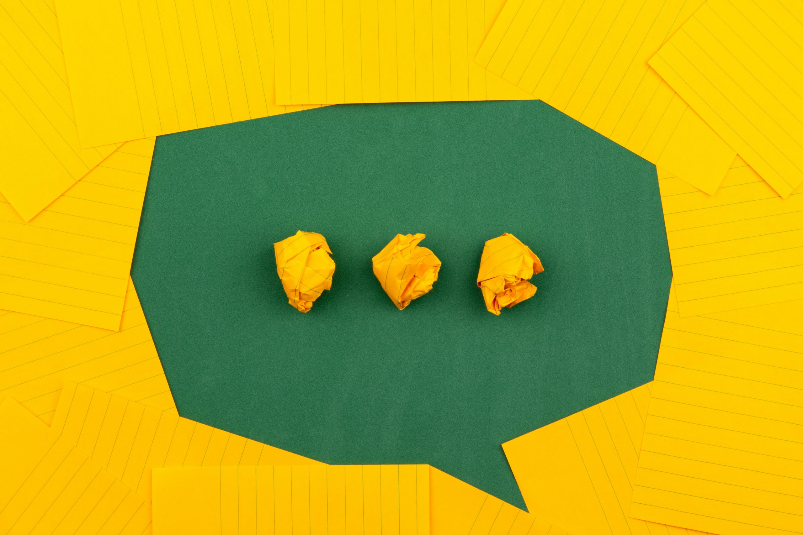 Photo by Volodymyr Hryshchenko three crumpled yellow papers on green surface surrounded by yellow lined papers